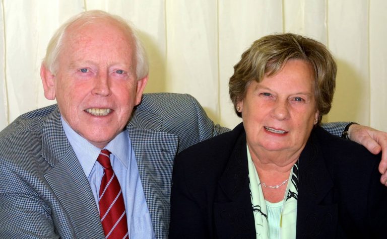 Eddie and Marion sitting together smiling at camera. min