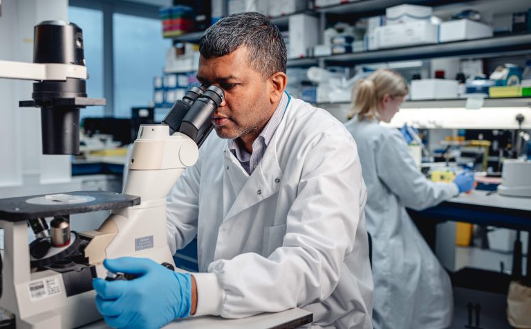 Researcher looking into a microscope