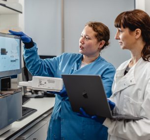 Two female researchers looking at a screen machine