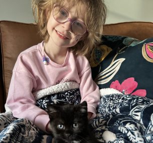 Dulcie smiling holding a black cat