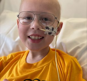 Harrison smiling in hospital bed with tube in nose